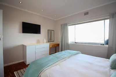 a bedroom with a bed and a tv and a window at Westward HO Apartment 13 in Cape Town
