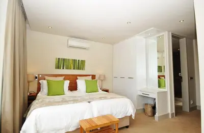 a bedroom with a large bed with green pillows at bamboo @ Le Paradis in Hermanus