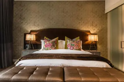a bedroom with a large bed with two lamps at Franschhoek Boutique Hotel - Lion Roars Hotels & Lodges in Franschhoek