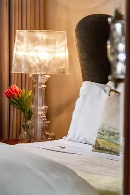 a bed with a lamp and a pillow and a vase of flowers at Nicara to Akker Collective in Stellenbosch