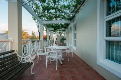 a patio with a table and chairs on a balcony at Clos Malverne Wine Estate in Stellenbosch
