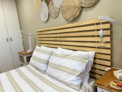 a bedroom with a bed with a wooden headboard and pillows at 10 On Ou Kraal in Edgemead