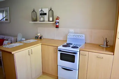 a kitchen with a white stove and wooden cabinets at 10 On Ou Kraal in Edgemead