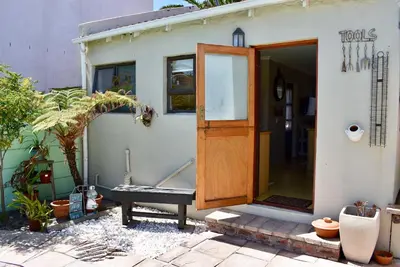a house with a wooden door and a bench outside at 10 On Ou Kraal in Edgemead