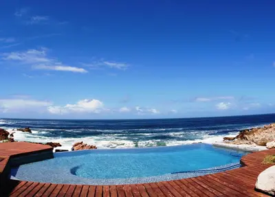 a swimming pool with the ocean in the background at Villa Marine Guest House in Pringle Bay