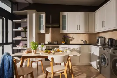 a kitchen with white cabinets and a table and chairs at 22 Eikehoff Apartment in Stellenbosch