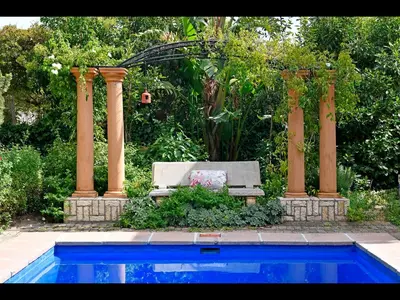 a garden with a bench next to a pool at Petit & Grande Plaisir luxury self-catering in Franschhoek