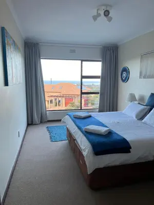a bedroom with a large bed and a large window at Hermanus Heights Villa in Hermanus