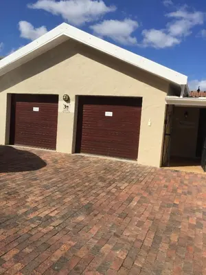two garage doors on a house with a brick driveway at Hermanus Heights Villa in Hermanus
