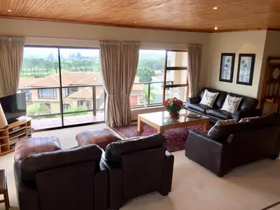 a living room with leather furniture and a large window at Hermanus Heights Villa in Hermanus