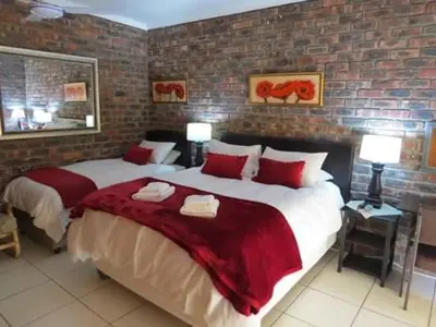 a bedroom with two beds and a brick wall at Coral Tree Guest Rooms in Worcester