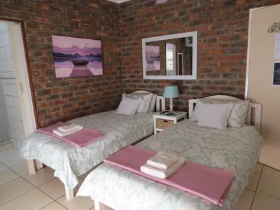 a bedroom with two beds and a brick wall at Coral Tree Guest Rooms in Worcester