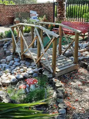 a wooden bridge with a bench in a garden at Coral Tree Guest Rooms in Worcester