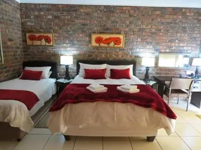 a bedroom with two beds and a brick wall at Coral Tree Guest Rooms in Worcester