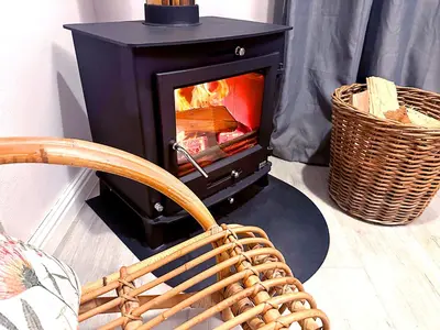 a wood burning stove with a chair in front of it at Onrus Cottage in Hermanus