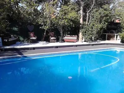 a blue swimming pool with two chairs and trees at Port House in Bloubergstrand