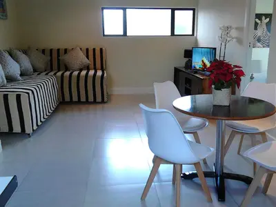a living room with a table and chairs and a couch at Port House in Bloubergstrand