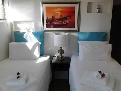 two beds in a hotel room with towels on them at Port House in Bloubergstrand