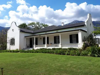 a white house with a lawn in front of it at Le Manse in Franschhoek