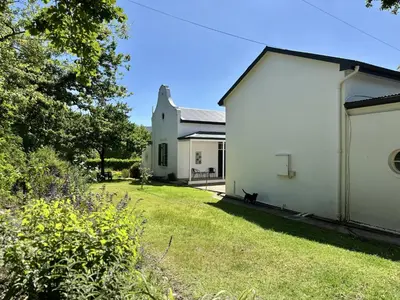 a cat sitting next to a white building at Le Manse in Franschhoek