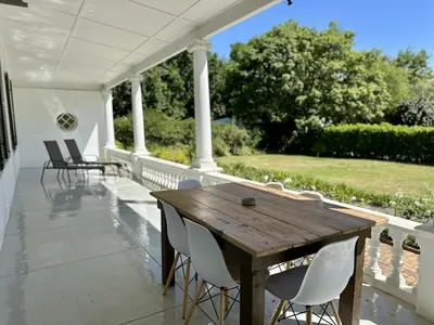 a wooden table and chairs on a porch at Le Manse in Franschhoek