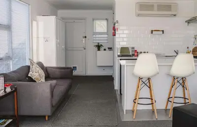 a living room with a couch and a kitchen at Brookwood Cottage in Somerset West