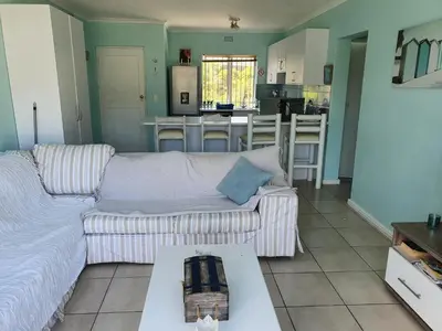 a living room with a couch and a kitchen at Sea and Mountain View Apartment in Gordonʼs Bay