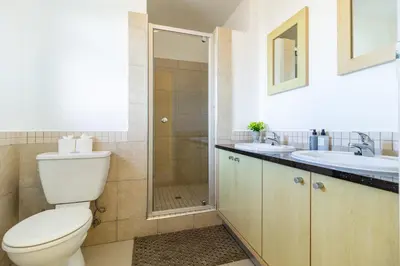 a bathroom with a toilet and a shower and a sink at Citystay Apartments Century City in Cape Town