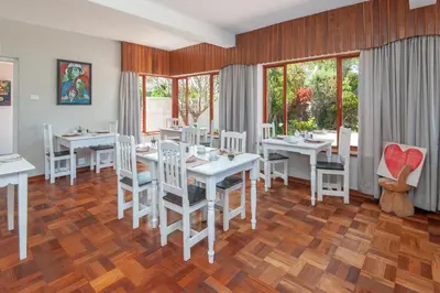 a dining room with white tables and white chairs at 6 Stemmet Lodge in Hermanus