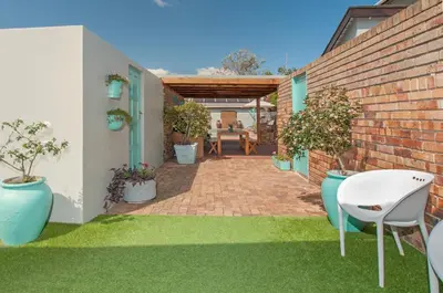 a patio with potted plants and a brick wall at 6 Stemmet Lodge in Hermanus