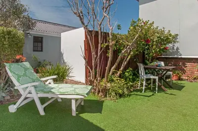 a garden with two chairs and a table on grass at 6 Stemmet Lodge in Hermanus