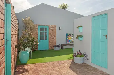 a patio with blue doors and potted plants at 6 Stemmet Lodge in Hermanus