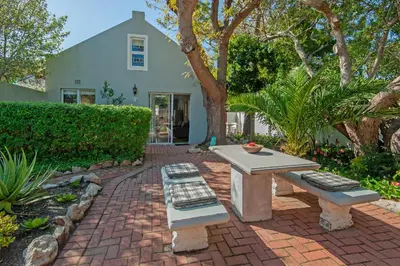 a patio with a table and benches in front of a house at 6 Stemmet Lodge in Hermanus