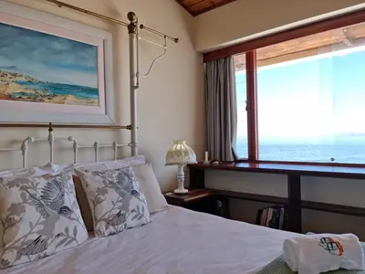 a bedroom with a bed and a large window at Bikini Beach Holiday Home, On the Beach, Sleeps 9! in Gordonʼs Bay