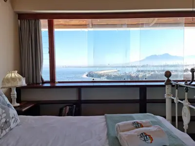 a bedroom with a large window with a view of the ocean at Bikini Beach Holiday Home, On the Beach, Sleeps 9! in Gordonʼs Bay