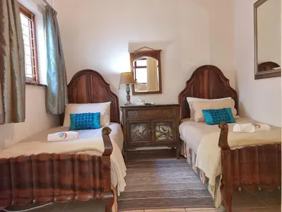 a bedroom with two beds and a mirror at Bikini Beach Holiday Home, On the Beach, Sleeps 9! in Gordonʼs Bay