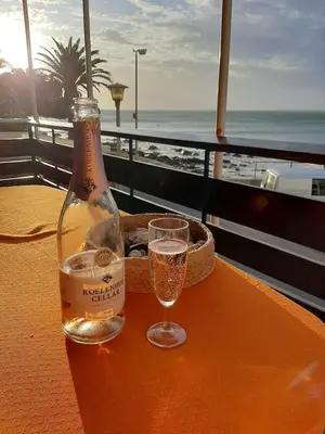 a bottle of champagne sitting on a table with a glass at Bikini Beach Holiday Home, On the Beach, Sleeps 9! in Gordonʼs Bay