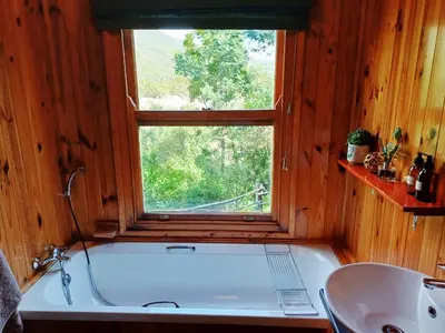 a bathroom with a tub and a sink and a window at The River Siding in Wolseley