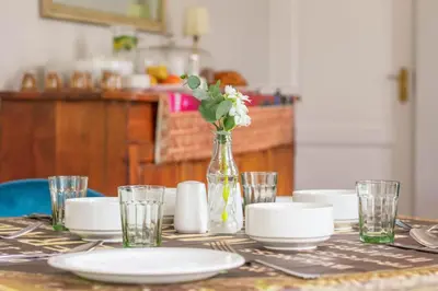 a table with plates and a vase with flowers on it at Rozenburg Guest House in Stellenbosch