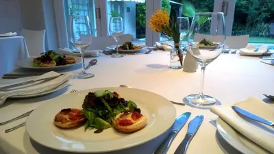 a table with a plate of food and wine glasses at Wild Olive Guest House & Villa in Cape Town