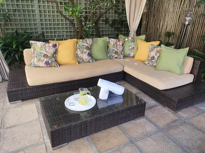 a couch with pillows and a table on a patio at Wild Olive Guest House & Villa in Cape Town