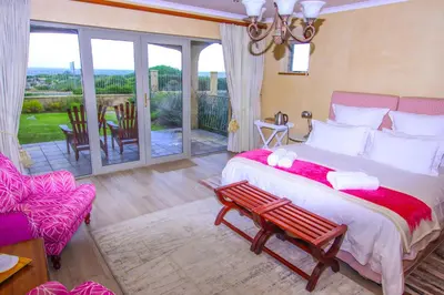 a bedroom with a large bed and a balcony at On The Cliff Guest House in Hermanus