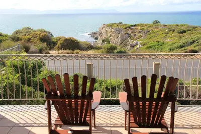 two chairs sitting on a balcony looking at the ocean at On The Cliff Guest House in Hermanus