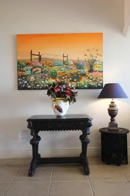 a vase sitting on a table next to a painting at On The Cliff Guest House in Hermanus