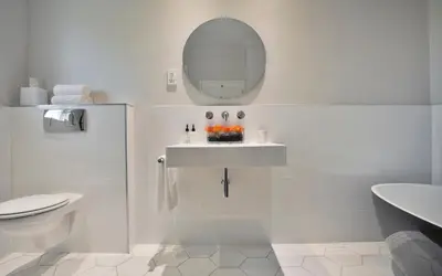 a white bathroom with a sink and a mirror at Sugarbird Manor in Stellenbosch