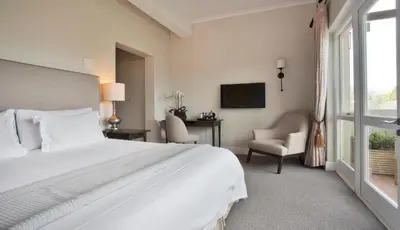 a bedroom with a large white bed and a window at Sugarbird Manor in Stellenbosch