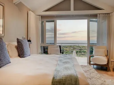 a bedroom with a large bed with a view of the ocean at Abalone Guest Lodge in Hermanus