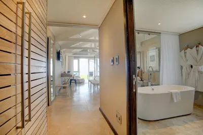 a bathroom with a tub and a hallway with a room at Abalone Guest Lodge in Hermanus