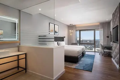 a bedroom with a bed and a desk and a sink at Cape Town Marriott Hotel Crystal Towers in Cape Town