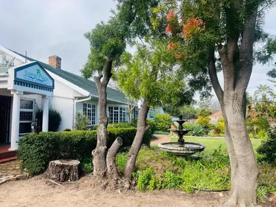 a house with a fountain and trees in the yard at Somer Place B&B in Somerset West